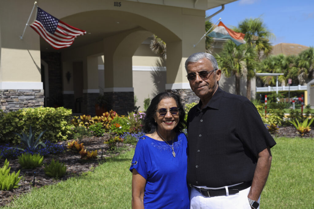 (Left) Puspa Tijoriwal, 72, and (right) Suresh Tijoriwal, 74, both from Virginia, pose in front of Anand Vihar, a 55-plus residential community located in Wesley Chapel. July 16, 2025.