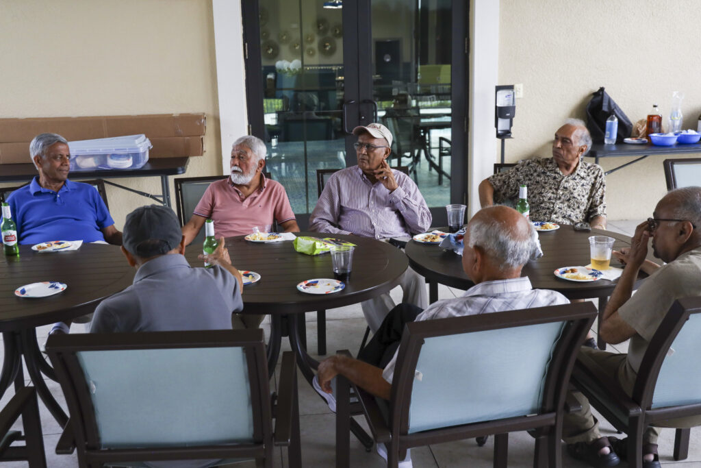 (From left) Suresh Tijoriwal, 74, Pavan Gupta, 80, Anil Shukla, 80, Ashok Kuber, 82, Jasubhai Bakriwala, 80, Chunilal Kansagra, 78, and Rajesh Pandya, 72, sit on the pool patio of Anand Vihar. Every week, male residents of Anand Vihar gather together to enjoy drinks and snacks. “Happy Hour” club has been a gathering at Anand Vihar for five years, and was one of the first resident-organized clubs. Anand Vihar is a 55-plus residential community located in Wesley Chapel. July 16, 2025.