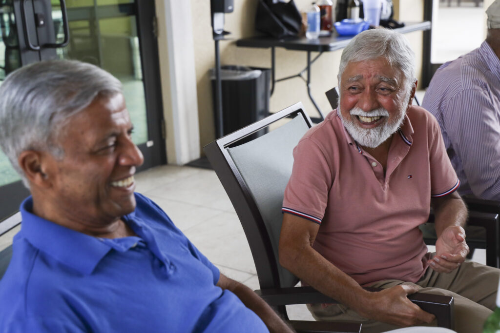 (Left) Suresh Tijoriwal, 74, and (right) Anil Shukla, 80, laugh together at “Happy Hour.” Every week, residents of Anand Vihar gather together to enjoy drinks and snacks. “Happy Hour” club has been a gathering at Anand Vihar for five years, and was one of the first resident-organized clubs. Anand Vihar is a 55-plus residential community located in Wesley Chapel. July 16, 2025.