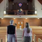 Rev. Maria Tjeltveit and Jessica Entwistle walk through the pews of the Church of the Mediator in Allentown, Pennsylvania. (Photo by Kabir Burman.)